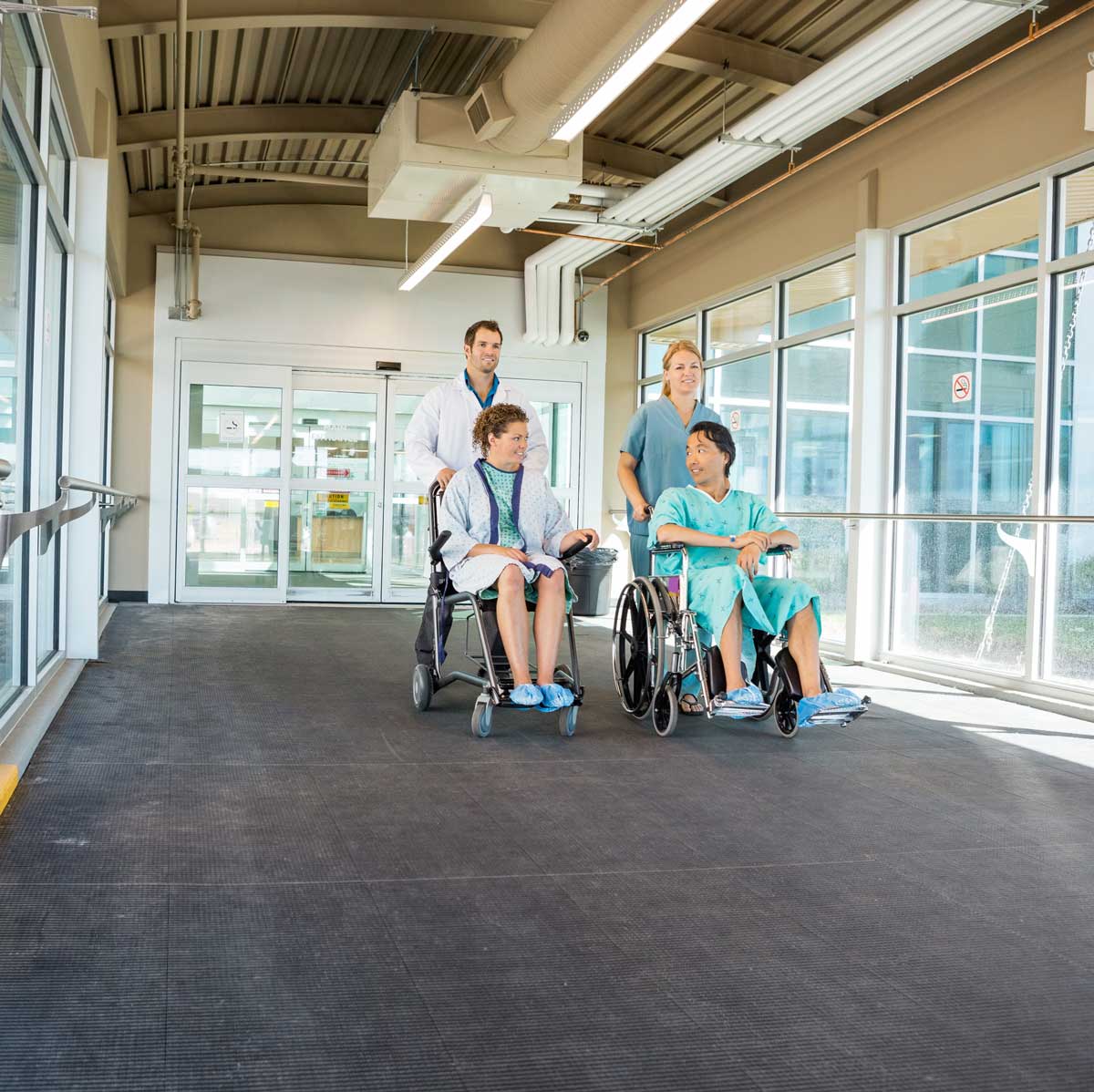 Medical Team Pushing Patients On Wheelchairs At Hospital Corridor